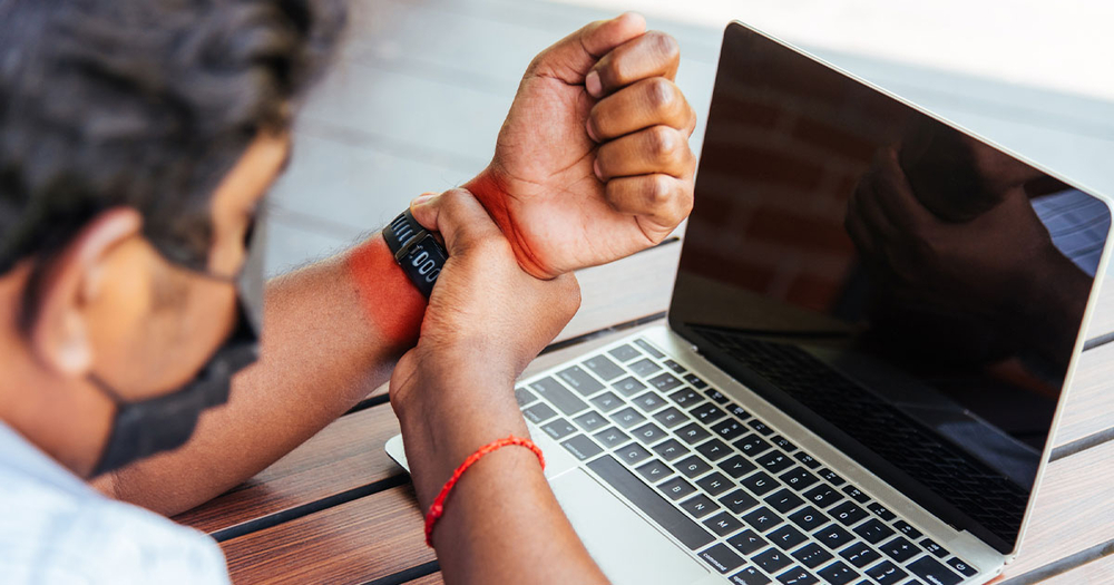 Man holding wrist while working on computer