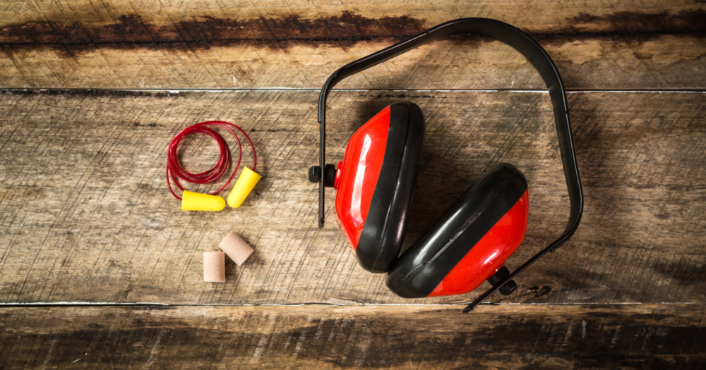 Ear muffs and ear plugs for industrial safety sitting on a wodden table.