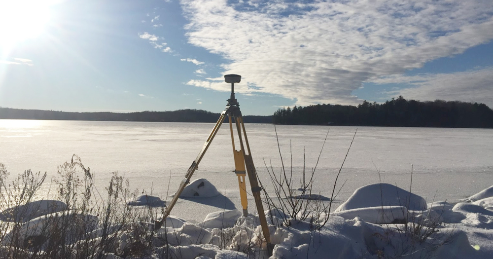 A yellow survey tripoid in the snow.