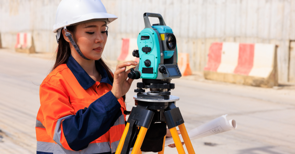 A women in an organe vest calibrating her survey instrument.