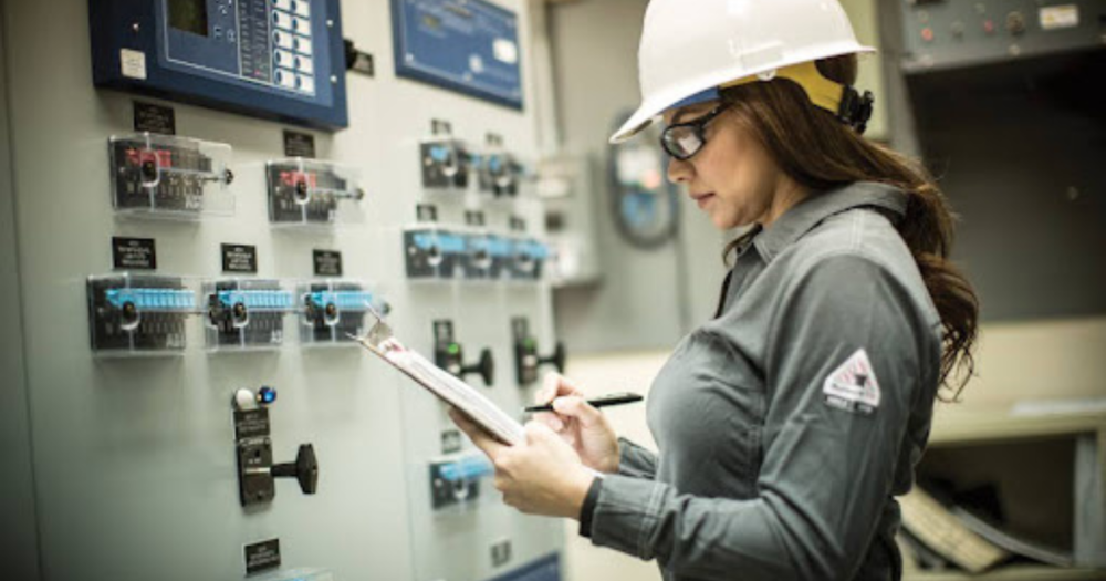 A woman working electrical wearing a white hardhat.