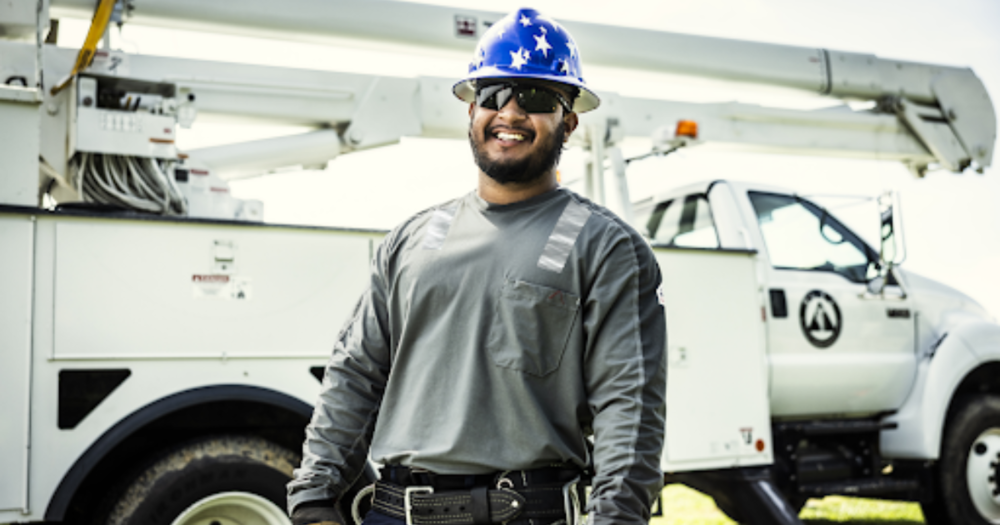 A man wearing a blue hardhat Baseline Equipment Co. smiling.