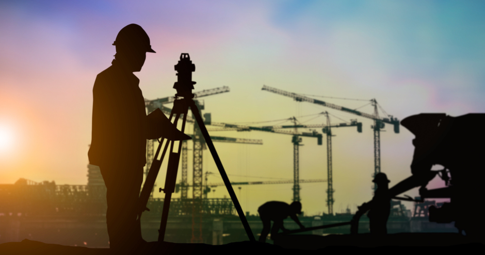 A man using real time kinectic (RTK) land surveying equipment on a construction site.