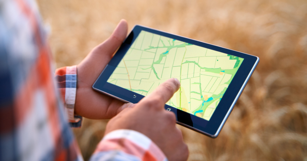 A man looking at his screen devise at readings from a GPS land survey.