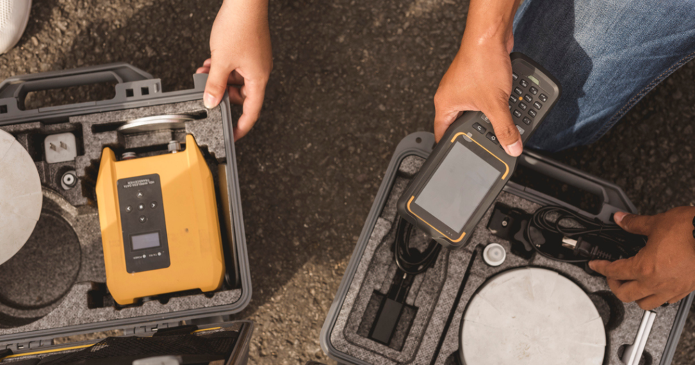 Two people going through protective cases with GPS land survey equipment to preform routine maintence.