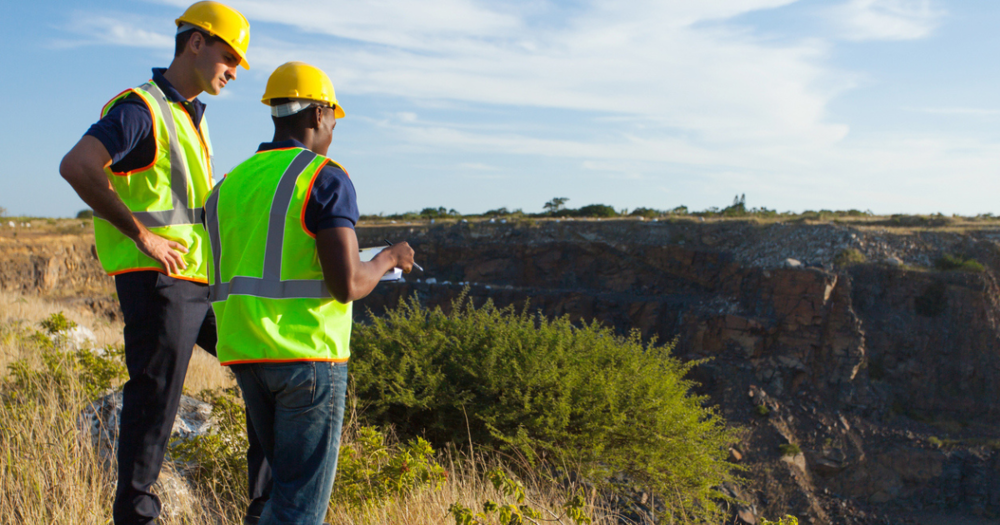 Two land surveryors at a mining site discussing GPS land surveying data.