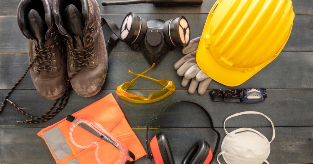 A hard hat, gloves, glasses, and other PPE on a table.